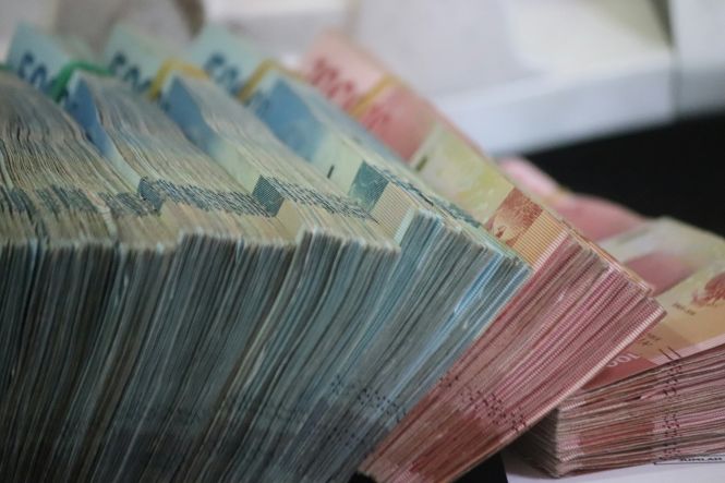 A stack of money bills on a table. Photo by Mufid Majnun on Unsplash