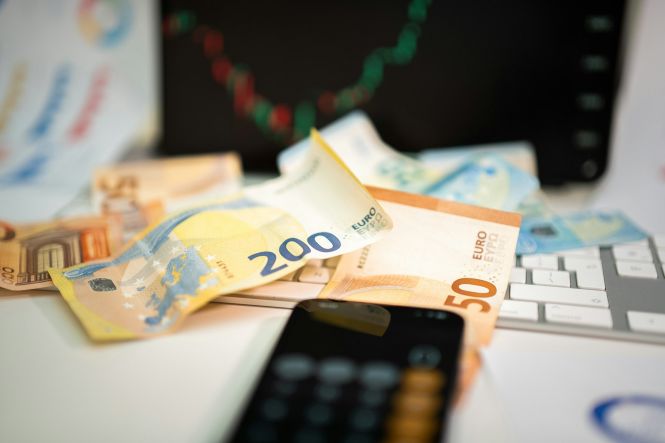 Euro banknote collection on a wooden surface. Photo by Jakub Żerdzicki on Unsplash