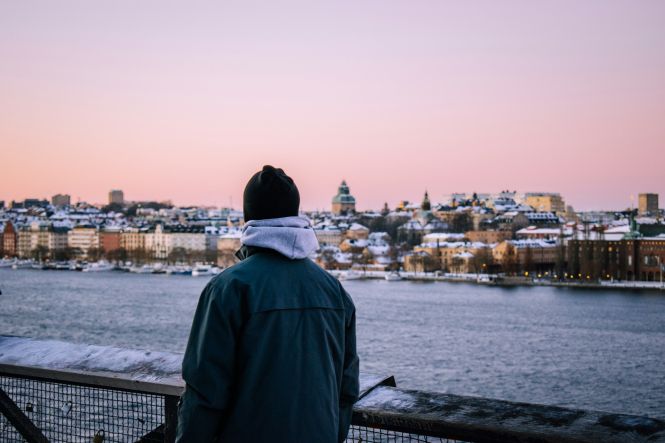 A person standing on a bridge looking at the water. Photo by Max van den Oetelaar on Unsplash